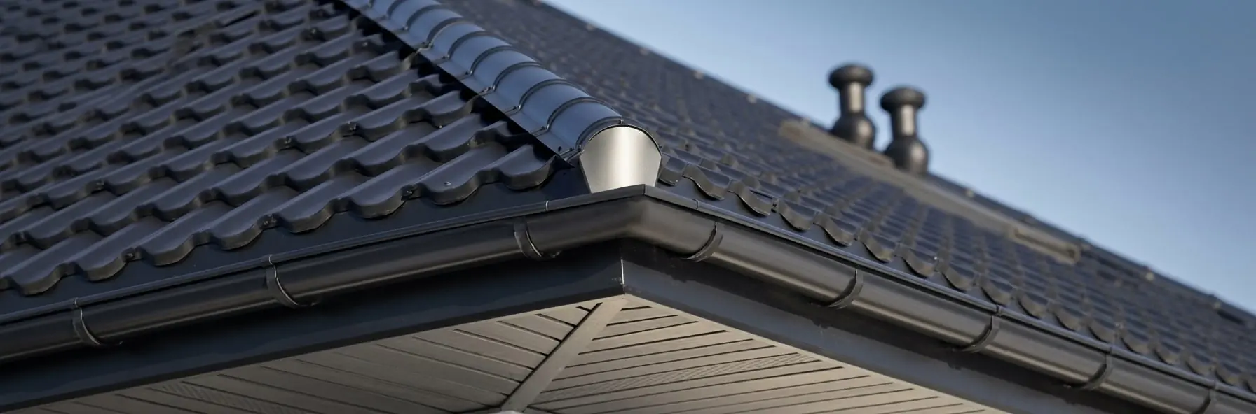 Clean guttering and spouting running along the edge of a dark tiled roof